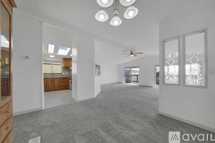 A spacious living room with a ceiling fan and large windows.