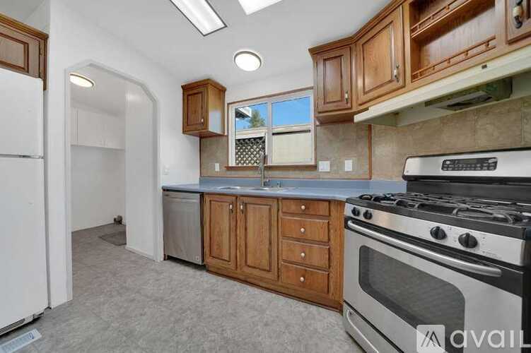A kitchen with wooden cabinets and a white stove top oven.