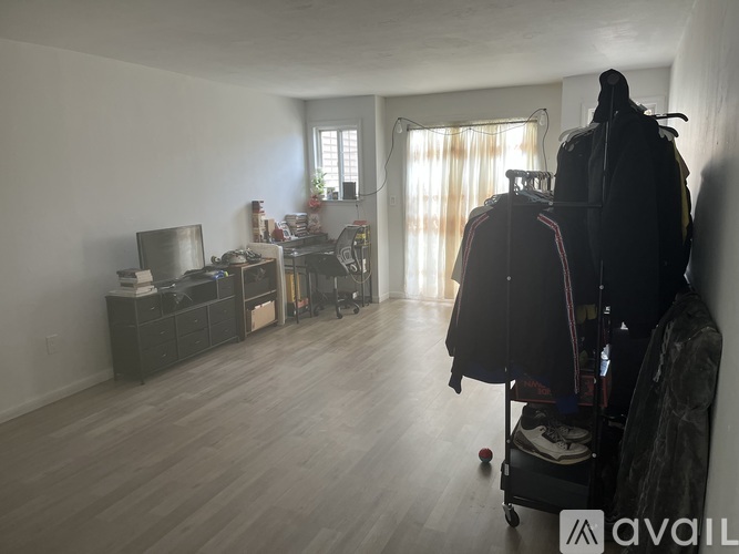 A room with a TV, a chair, and a suitcase on a cart.
