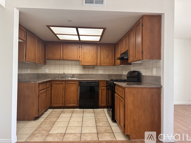 A kitchen with brown cabinets and black appliances.