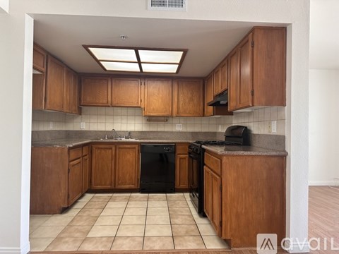 A kitchen with brown cabinets and black appliances.