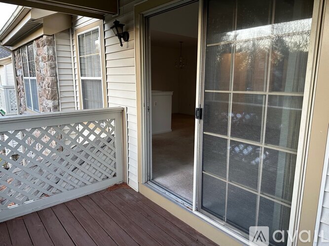 A deck with a lattice patterned railing and a glass door.