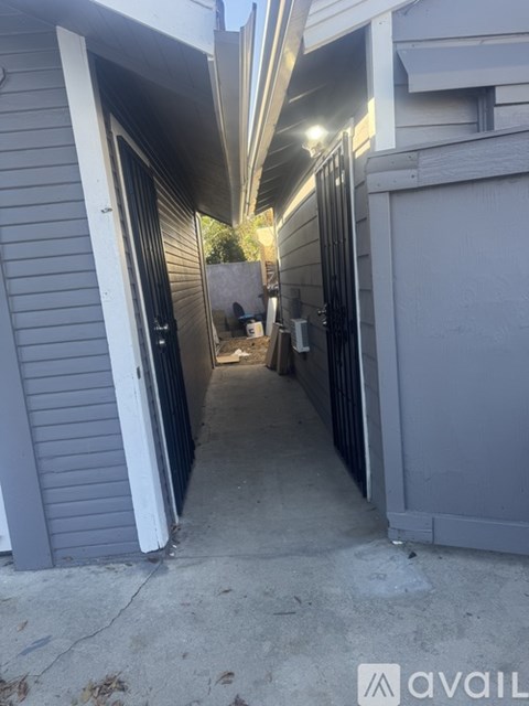 A narrow alleyway between two buildings with a sign that reads "avail".