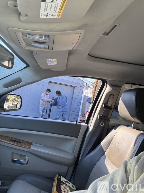Two people in blue suits are standing outside a vehicle.