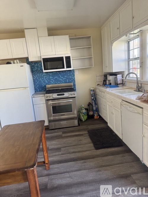 A kitchen with white cabinets and a blue backsplash.
