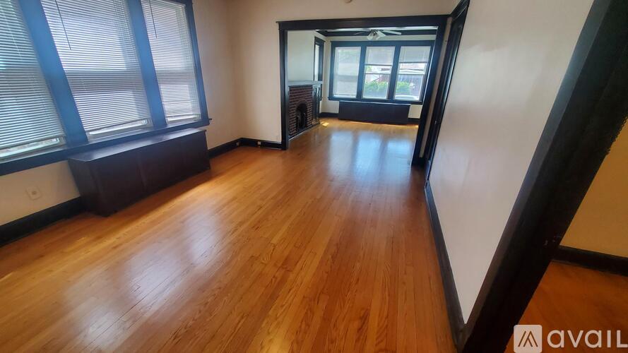 A room with wooden flooring and a large window with blinds.