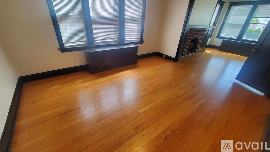 A room with wooden flooring and a window with blinds.