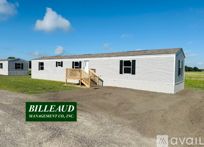A white building with the words Billeaud Management Co., Inc. on the ground in front of it.