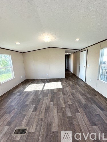 A room with wooden flooring and a window on the left side.
