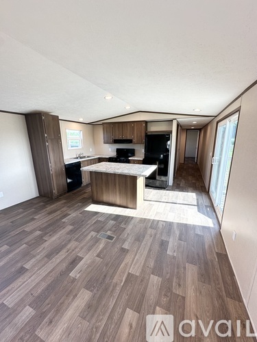 A spacious living room with a kitchen area in the background.
