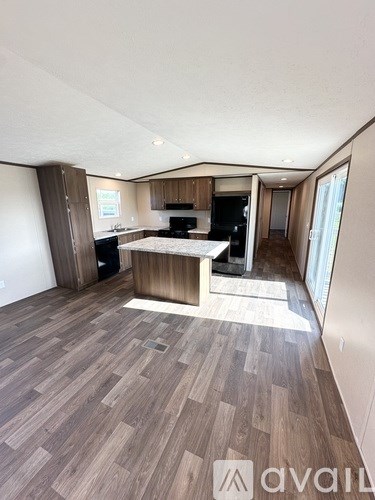 A spacious living room with a kitchen area in the background.