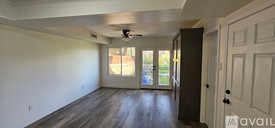 A room with a ceiling fan and a door leading to a balcony.
