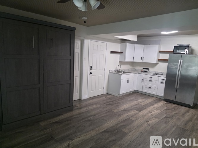 A kitchen with a refrigerator, cabinets, and a fan.