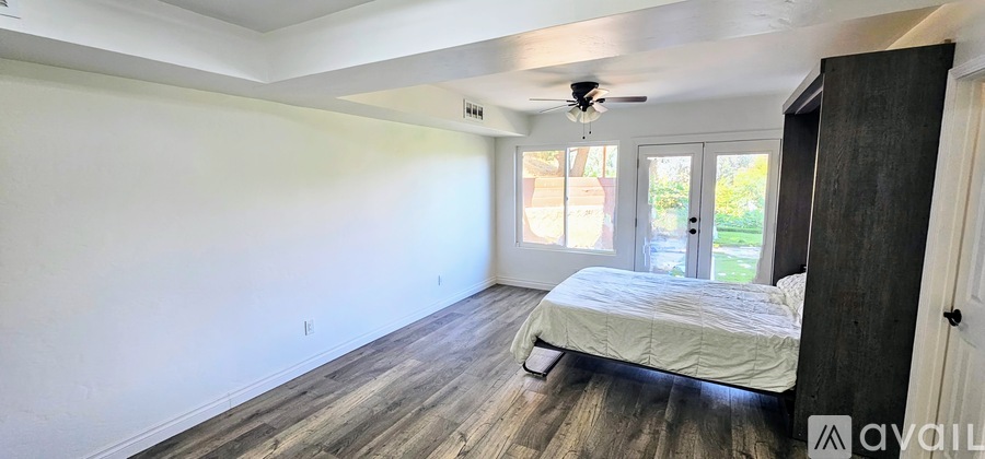 A bedroom with a bed, dresser, and sliding glass doors.