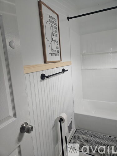 A white door with a handle and a wooden sign above it.