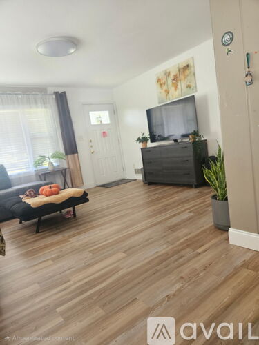 A living room with a couch, a television, and a wooden floor.