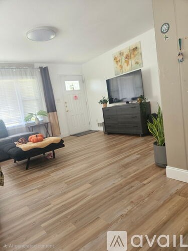 A living room with a couch, a television, and a wooden floor.