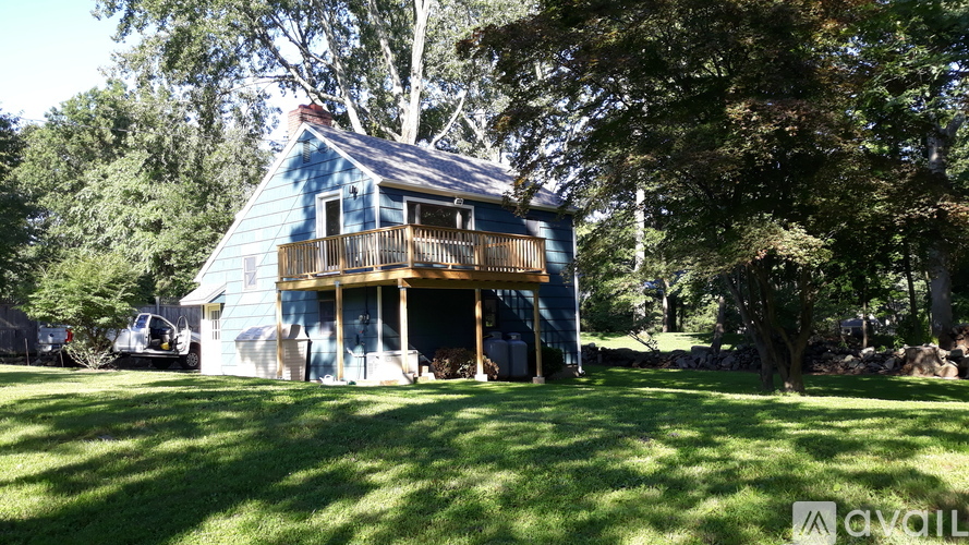 A blue house with a porch and a car parked in front.