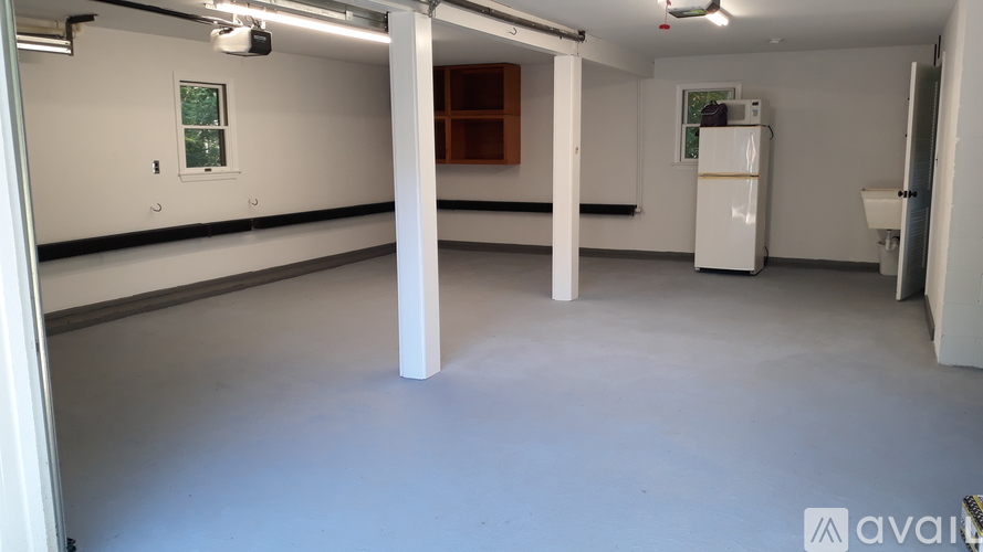 A spacious room with a white refrigerator and a window.