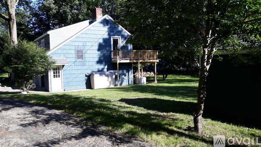 A blue house with a white door and windows is surrounded by trees.
