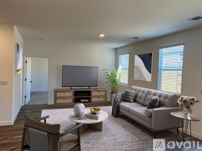A living room with a grey sofa, a white coffee table, and a television.