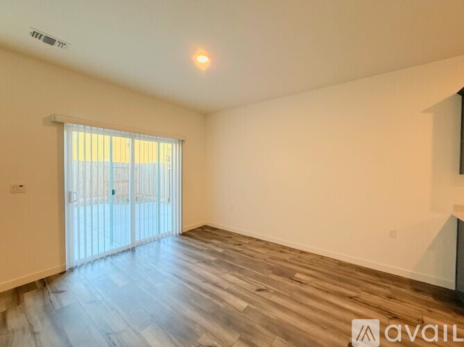 A spacious room with wooden flooring and a sliding glass door.