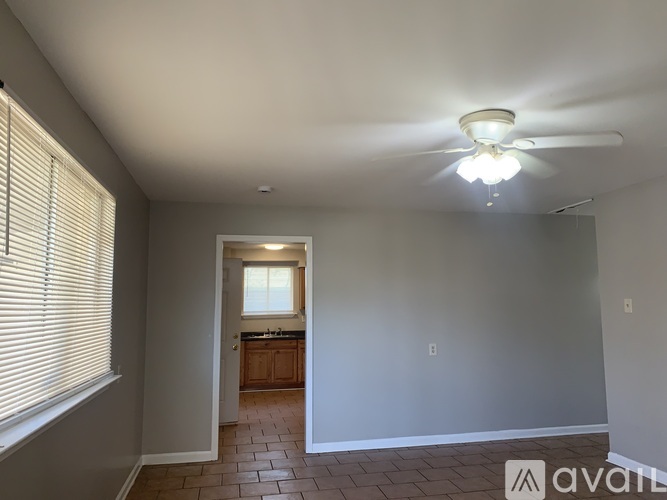 A room with a ceiling fan and a window with blinds.