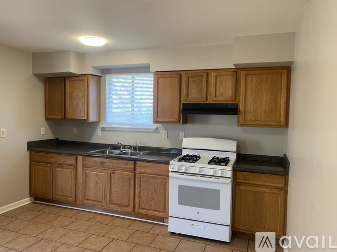 A kitchen with wooden cabinets and a white stove top oven.