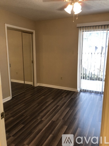 A room with wooden flooring and a window with blinds.