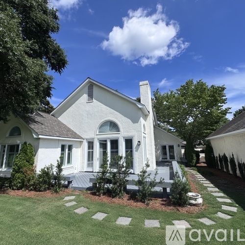 A white house with a large front porch and a stone pathway leading to the front door.