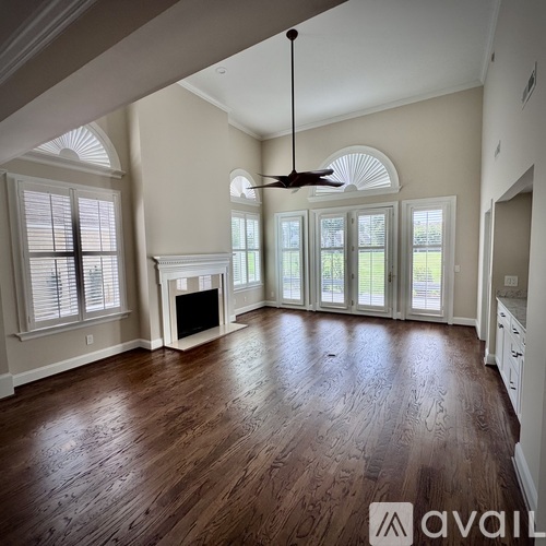 A spacious living room with wood flooring and a fireplace.