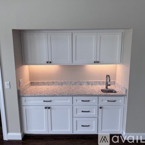 A kitchen with white cabinets and a marble countertop.