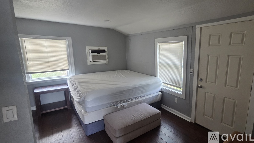 A bedroom with a large bed and a window with blinds.