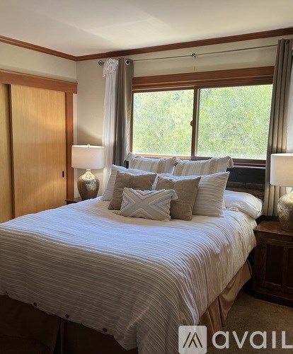 A bedroom with a large bed and a window with curtains.