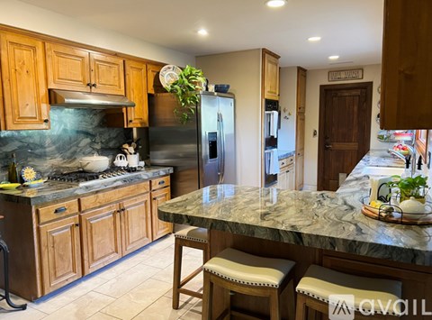 A kitchen with wooden cabinets and a marble countertop.