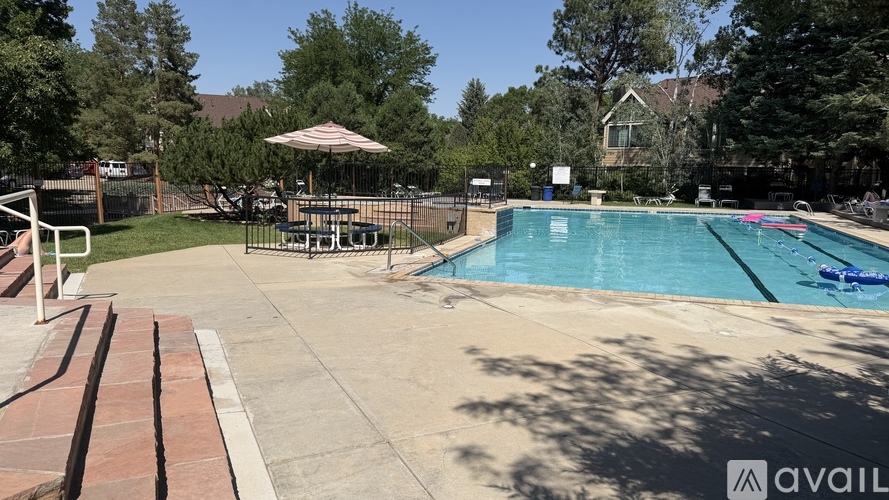 A pool with a sun umbrella and a diving board.