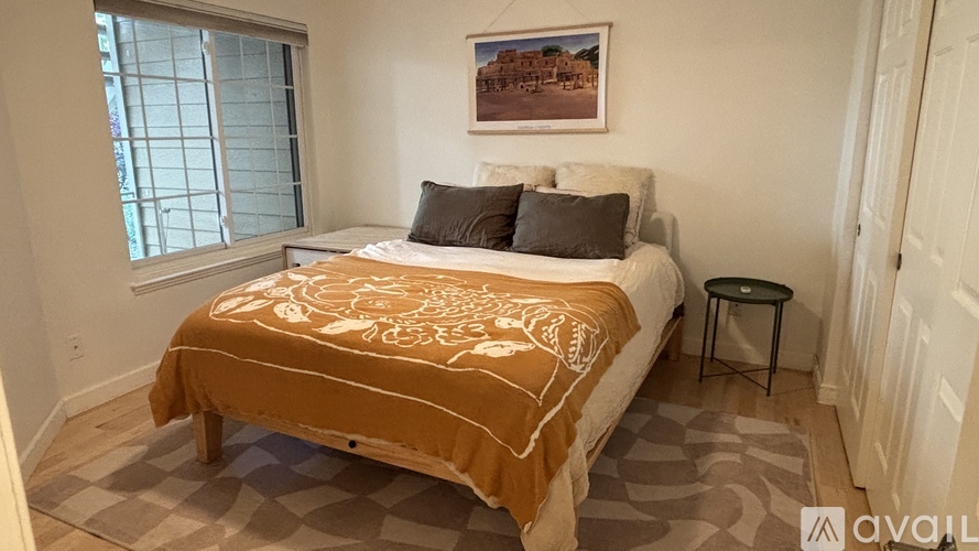 A bedroom with a bed covered in a patterned bedspread and two pillows.