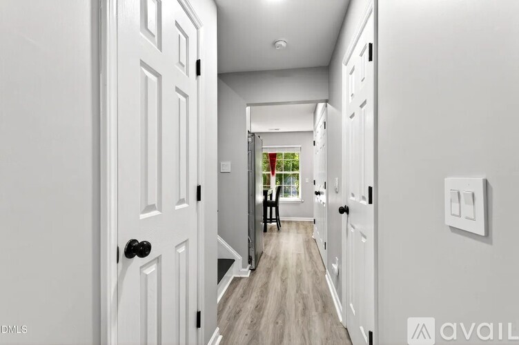 A hallway with white doors and a light switch on the wall.