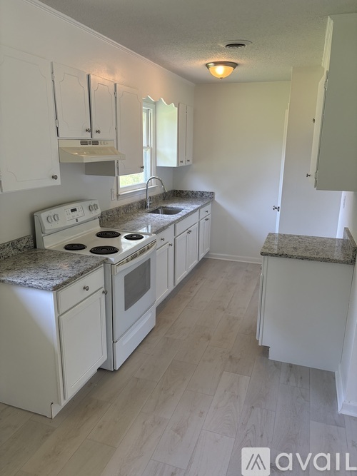 A kitchen with white cabinets and a granite countertop.
