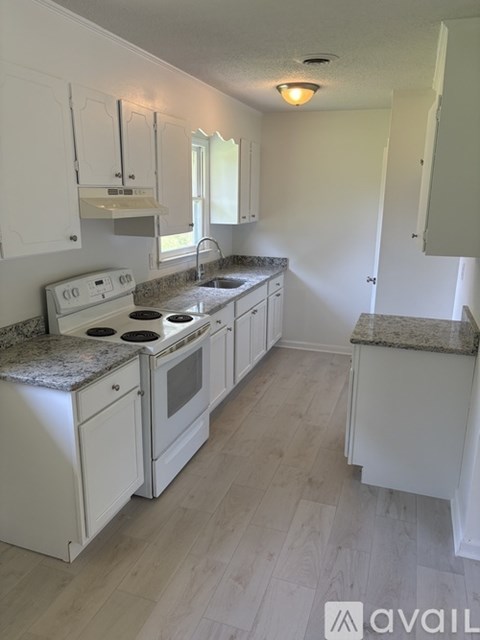 A kitchen with white cabinets and a granite countertop.