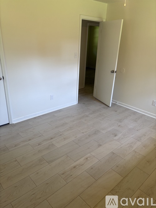 A room with a white door and a wooden floor.