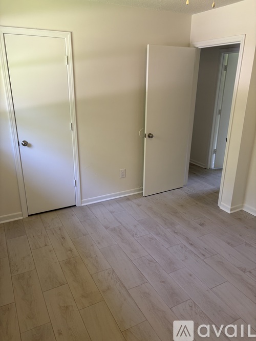 A room with two white doors and a wooden floor.