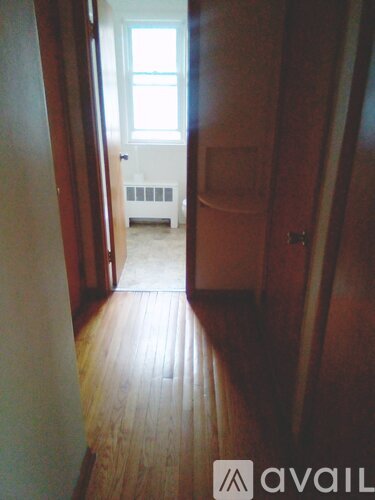 A hallway with wood floors and a door on the right.