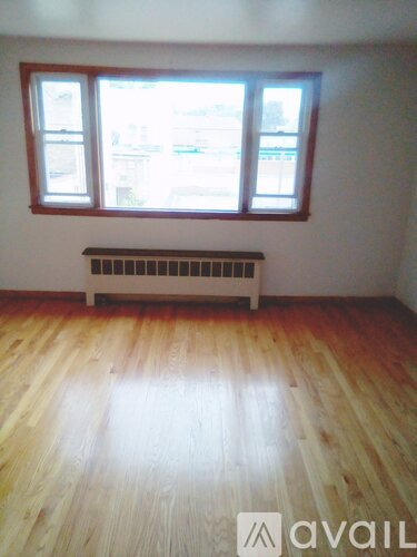 A room with wooden floors and a window with a radiator under it.