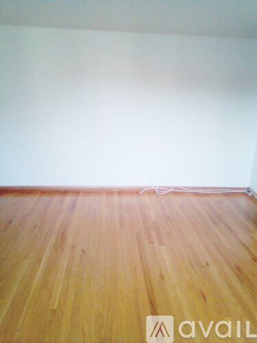 A room with wooden flooring and a white wall.