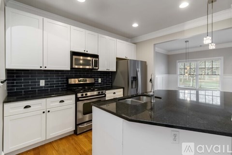 A kitchen with white cabinets and black countertops.