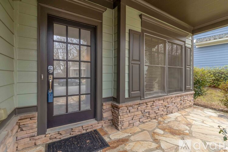 A house entrance with a brown door and a stone wall.