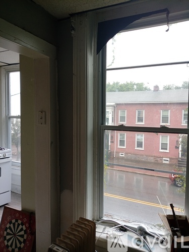 A view of a street through a window with a dartboard on the other side.