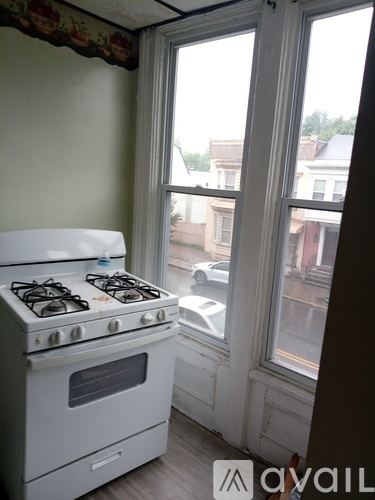 A white gas stove in a kitchen with a window showing a street view.