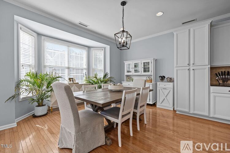 A dining room with a table set for four and a kitchen area in the background.